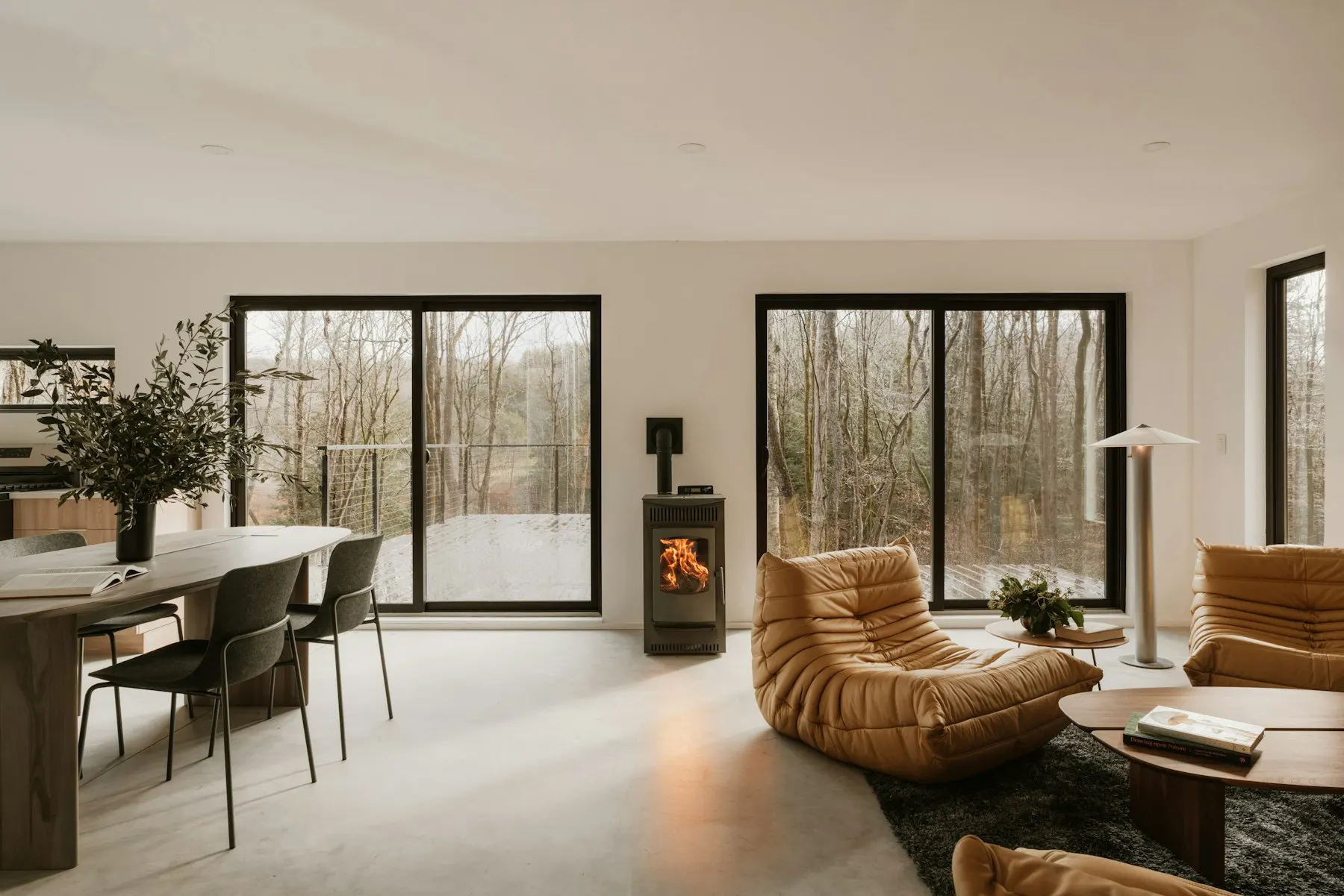 Salle à manger avec feu de cheminée et baie vitrée sur jardin — T4 Horizon